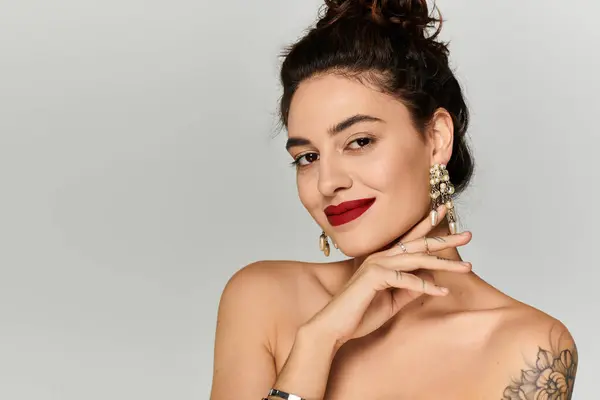 Una joven mujer hermosa posa con confianza, mostrando sus accesorios y maquillaje en un estudio. - foto de stock