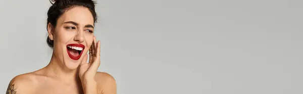 Bright smile of a young woman with dark hair and red lipstick on a plain backdrop. — Stock Photo