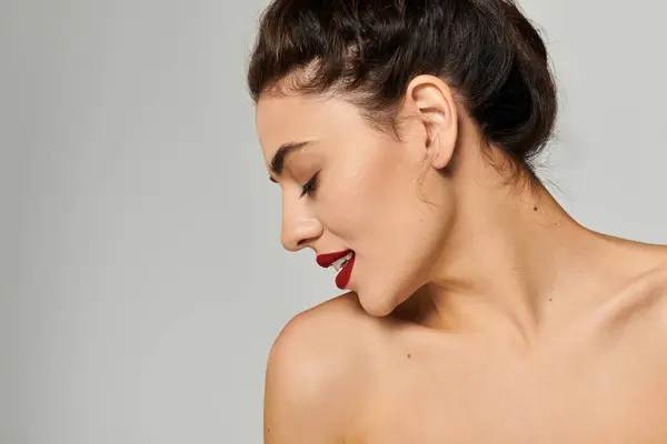 Une belle jeune femme aux cheveux longs élégamment coiffée pose avec une vue de profil gracieuse. — Photo de stock