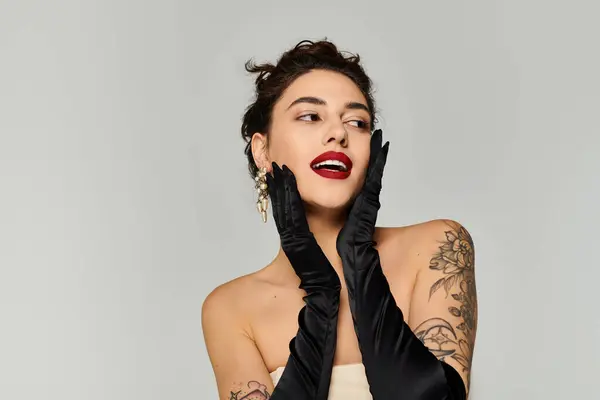 Woman with tattoos poses with black gloves and bold lipstick, showcasing elegance and charm. — Stock Photo