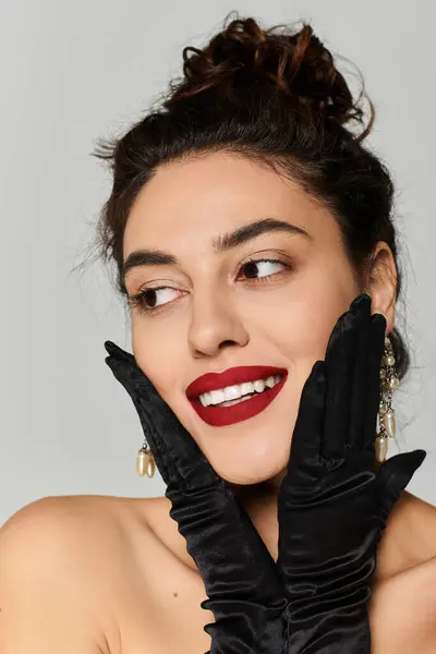 A young woman smiles playfully, posing with her gloved hands on her face. — Stock Photo