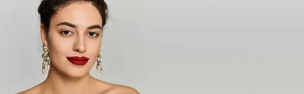 A young beautiful woman showcases her style with bold lipstick and elegant earrings while posing. — Stock Photo