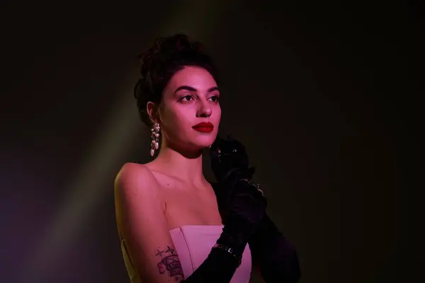 Eine atemberaubende Frau strahlt Eleganz mit stilvollen Handschuhen und glamourösen Ohrringen in sanftem Licht aus. — Stockfoto