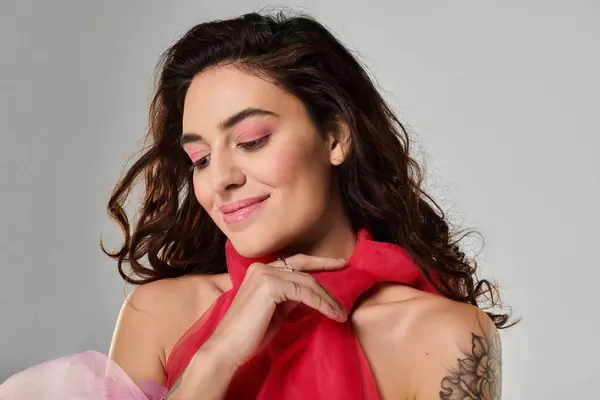A young woman with soft makeup holds a red scarf, showcasing her natural beauty in a studio. — Stock Photo