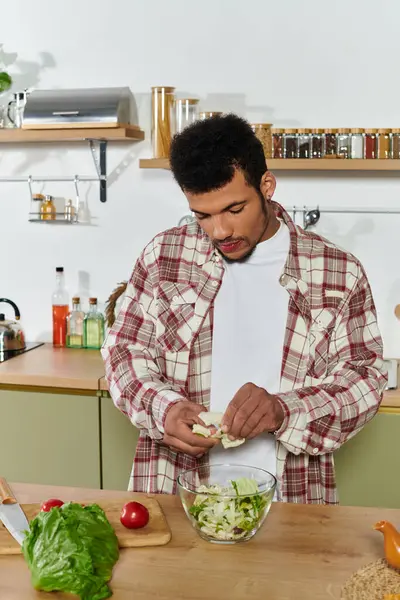 Handsome young man is chopping vegetables for a healthy salad in the kitchen. — Stock Photo