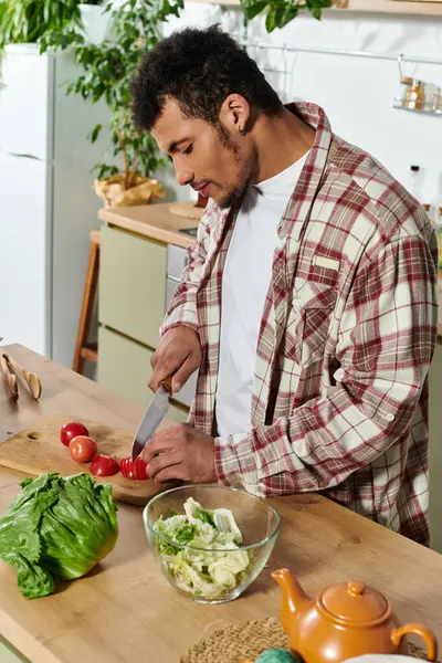 Handsome young man prepares fresh tomatoes for a nutritious meal in a welcoming kitchen. — Stock Photo