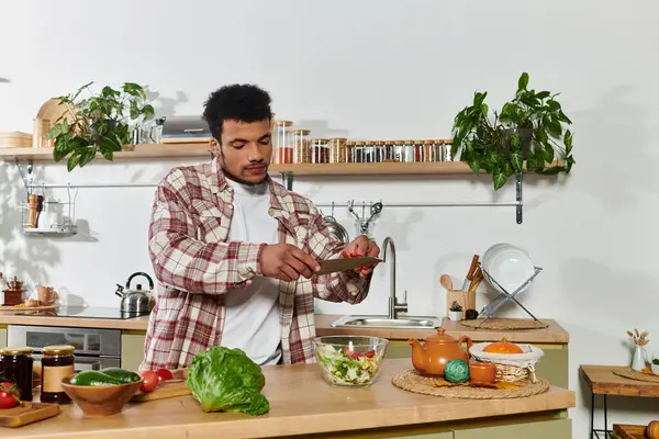 A young man skillfully chops vegetables while making a healthy salad in a bright kitchen. — Stock Photo