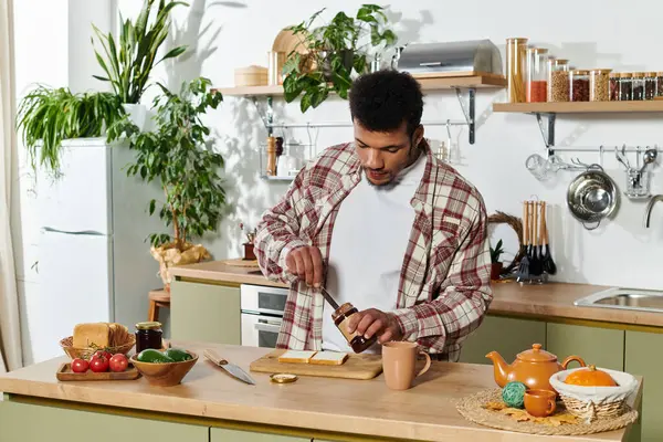 Handsome young man spreads jam on toast while enjoying a bright morning in the kitchen. — Stock Photo