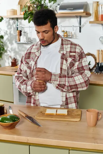 Um jovem bonitão de pé em uma cozinha, reunindo ingredientes para um sanduíche. — Fotografia de Stock