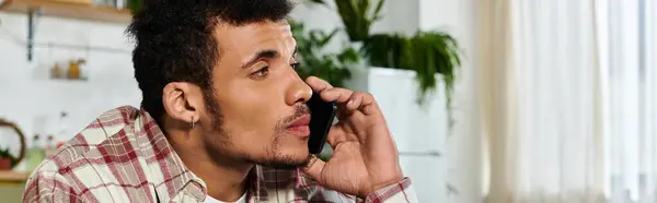 Handsome young man talks on the phone while sitting on a comfortable chair at home. — Stock Photo