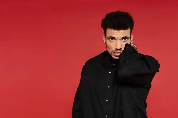 Young man showcases his style against a bold red backdrop while exuding confidence. — Stock Photo