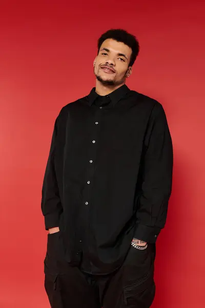 A handsome young man stands relaxed with a smile, dressed in a stylish black shirt. — Stock Photo