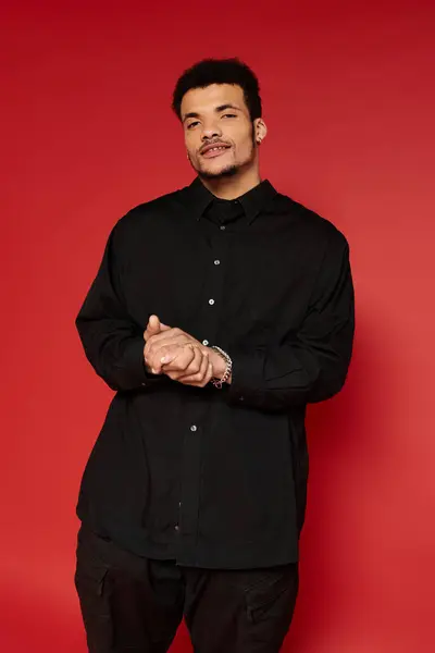 A young man stands with a relaxed posture, showcasing his style and charm, wearing a black shirt. — Stock Photo