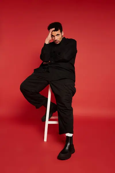 Stylish young man in black outfits with confident pose, creating a striking visual impact indoors. — Stock Photo
