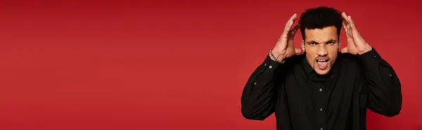 Handsome young man showing intense feelings while posing in front of a bright red backdrop — Stock Photo