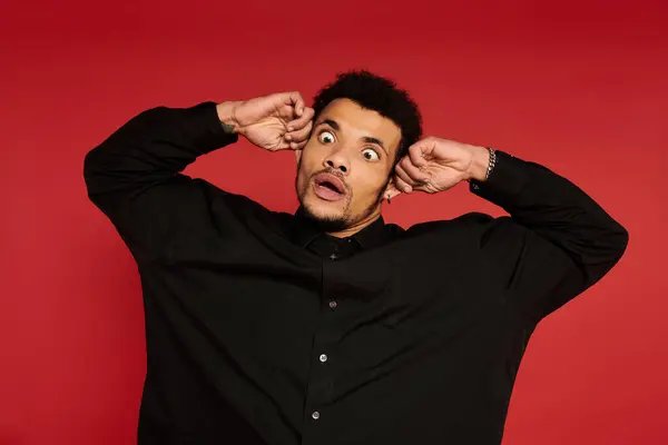 A young handsome man shows a surprised expression while holding his head with both hands. — Stock Photo