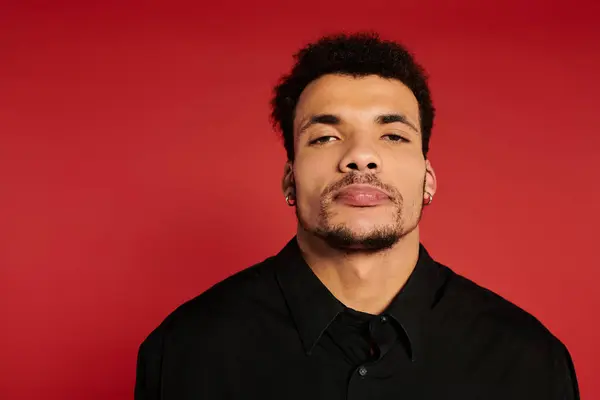 Handsome young man displaying a calm demeanor against a vibrant red backdrop. — Stock Photo
