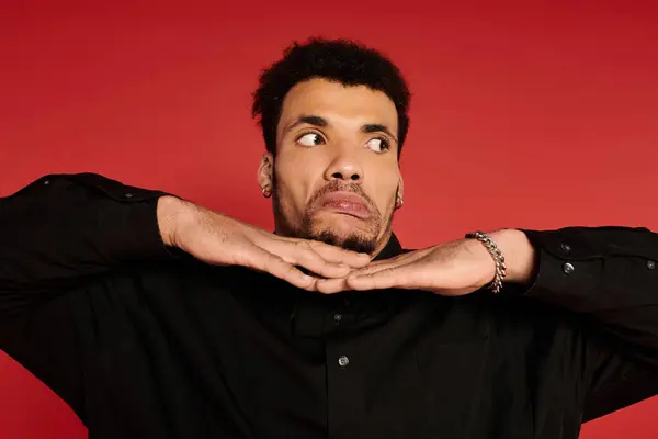 Young man displays a fun expression, hands raised near his chin, set against a vibrant red backdrop. — Stock Photo