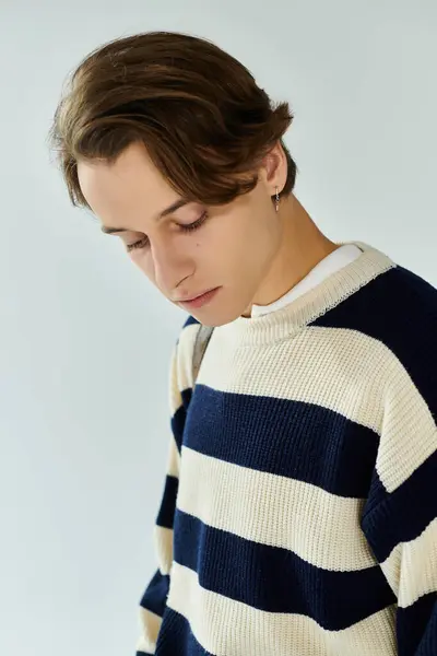 A young man in a stylish striped sweater reflects on his college experience in a studio. — Stock Photo