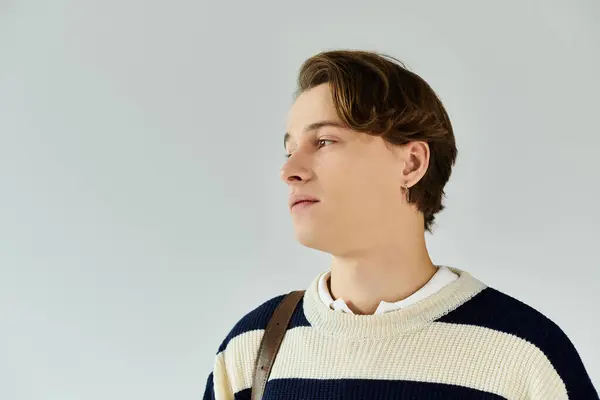 A young man wearing a striped sweater gazes thoughtfully, embodying youth and ambition. — Stock Photo