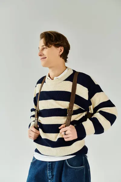 A handsome young man showcases his style in a striped sweater, capturing a moment of confidence. — Stock Photo