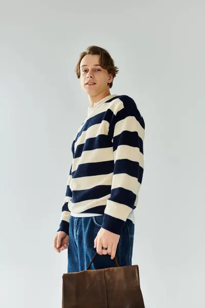 Young man in a striped sweater stands confidently in a studio setting, showcasing his style. — Stock Photo