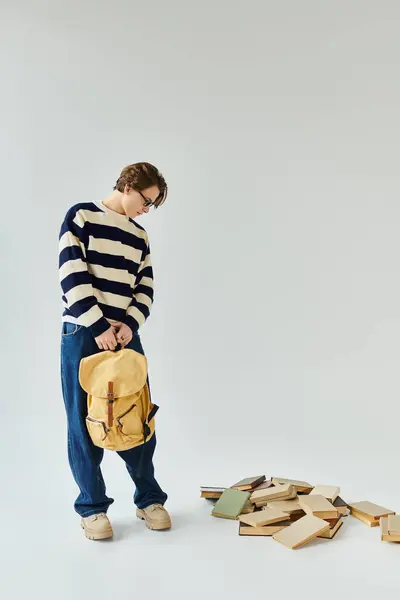 A young man stands in a studio adorned with books, reflecting his college journey and style. — Stock Photo