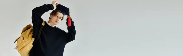 A handsome young man adjusts his graduation cap, showcasing pride in his achievement during college, banner — Stock Photo