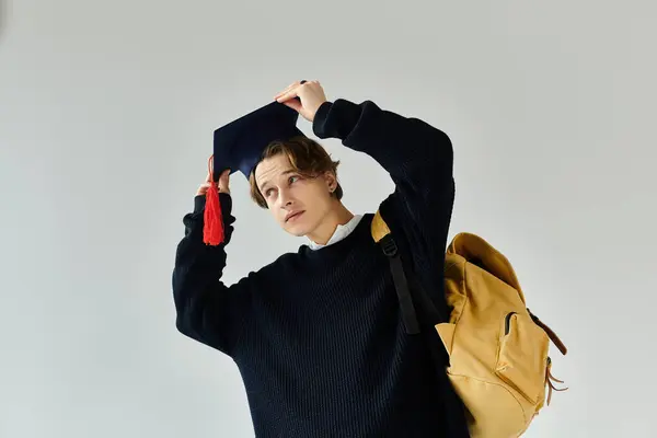 A young man adjusts his graduation cap while showcasing his college spirit and pride. — Stock Photo