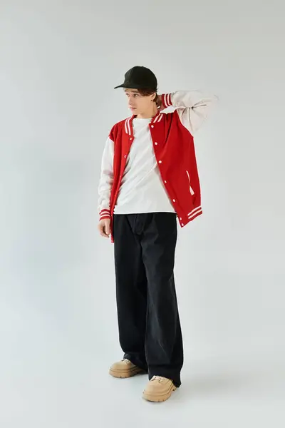 A handsome young man in a stylish bomber jacket stands thoughtfully in a contemporary studio. — Stock Photo