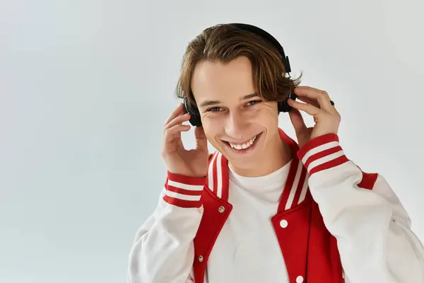 Jeune homme dans une veste bombardier à la mode sourit vivement tout en portant des écouteurs dans un studio. — Photo de stock
