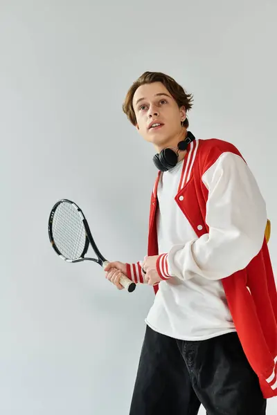 A young man dressed in a chic bomber jacket stands confidently in a studio, ready to engage. — Stock Photo