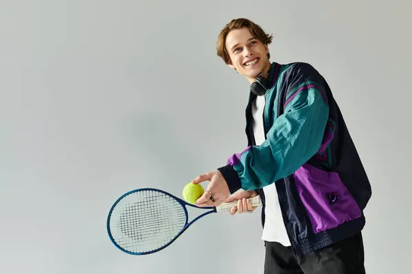 A handsome young man in a trendy bomber jacket is poised for tennis, smiling with enthusiasm. — Stock Photo