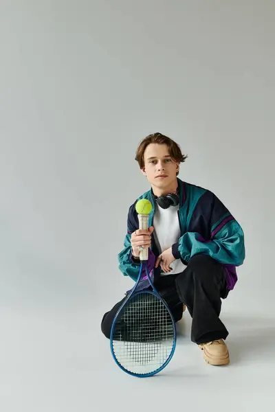 A confident young man poses with a tennis racket, showcasing his trendy casual style. — Stock Photo