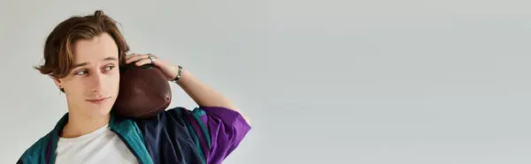 A handsome young man poses in a studio wearing a trendy bomber jacket, showcasing youth culture. — Stock Photo