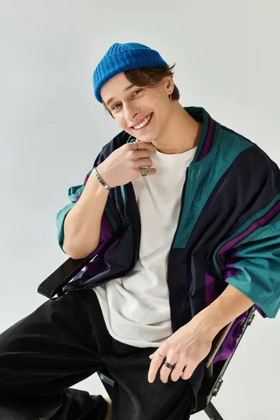 A handsome young man dons a fashionable bomber jacket in a studio setting, exuding confidence. — Stock Photo
