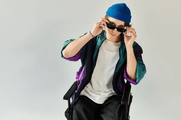 A handsome young man in a stylish bomber jacket adjusts his sunglasses thoughtfully. — Stock Photo