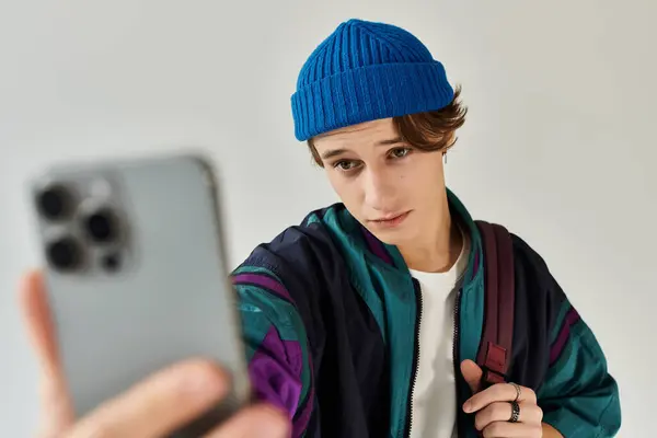 A handsome young man in a bomber jacket captures a selfie while posing in a trendy studio. — Stock Photo