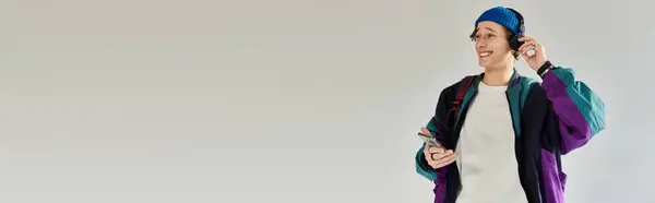 A young man in a trendy bomber jacket smiles while listening to music in a studio. — Stock Photo
