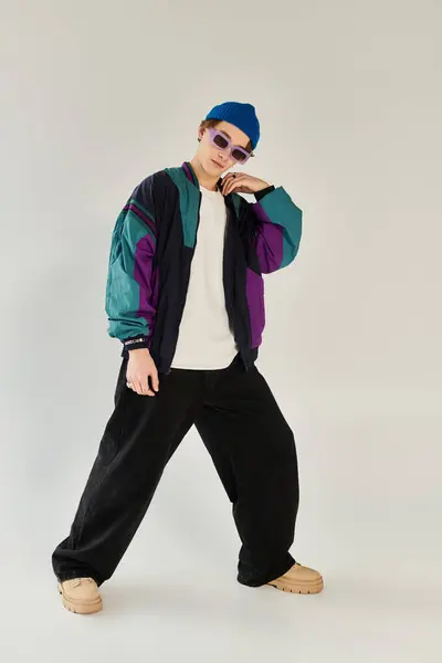 A young man poses confidently in a colorful bomber jacket within a modern studio. — Stock Photo