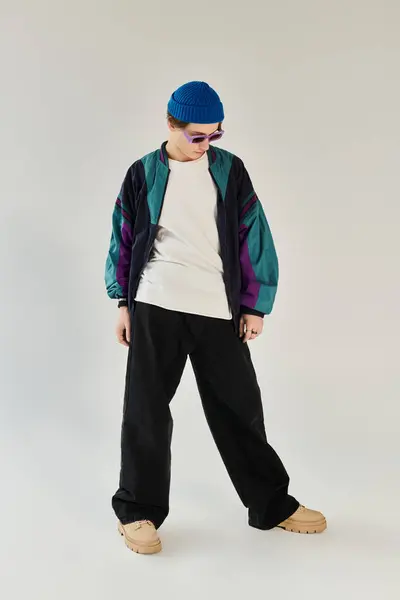 A young man stands confidently, wearing a stylish bomber jacket and relaxed pants, in a studio. — Stock Photo