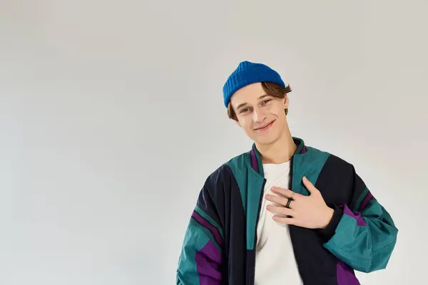 A handsome young man stands confidently, dressed in a colorful bomber jacket, in a studio. — Stock Photo