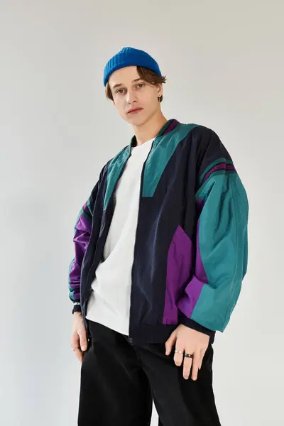 A young man in a fashionable bomber jacket stands in a studio, exuding confidence and style. — Stock Photo