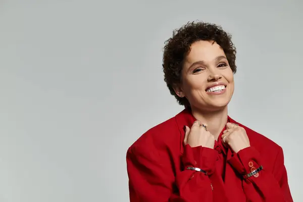 A radiant young woman in a red jacket poses playfully, showing her infectious smile. — Stock Photo