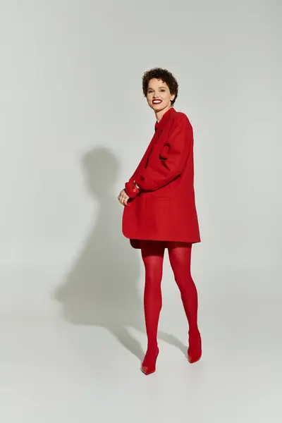 A stunning young woman strikes a playful pose in striking red attire, exuding confidence and charm. — Stock Photo