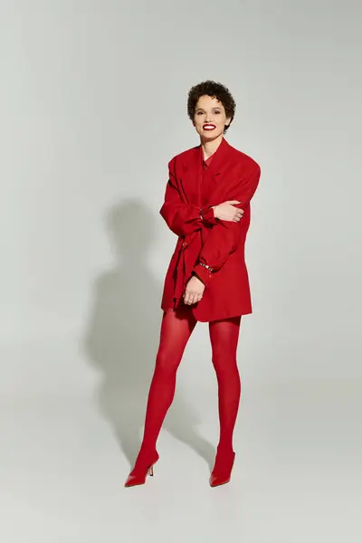 Stylish young woman showcases bold red attire while exuding confidence in a serene setting. — Stock Photo