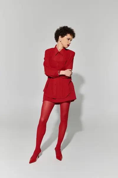 A young and beautiful woman elegantly poses in a vibrant red ensemble, radiating fashion and charm. — Stock Photo