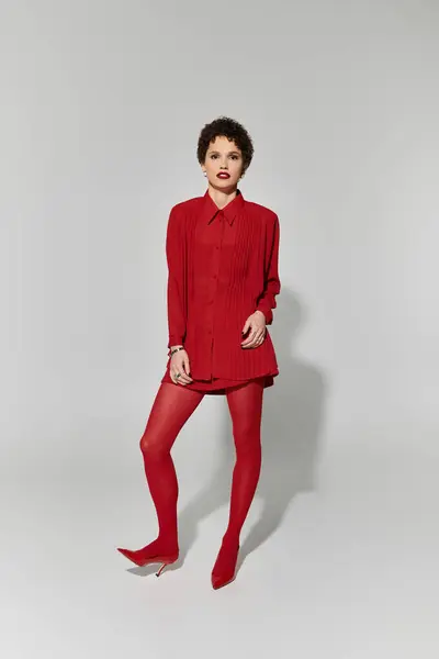 Confident young woman showcases bold fashion choices while posing gracefully in red attire. — Stock Photo