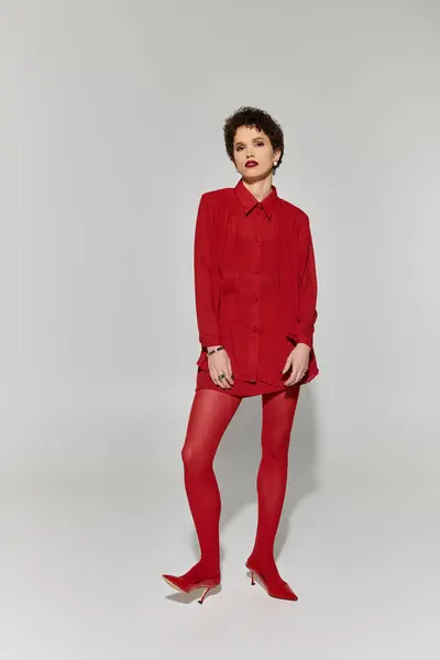 Jeune femme élégante en tenue rouge audacieuse se tient avec confiance, exsudant élégance et charme. — Photo de stock