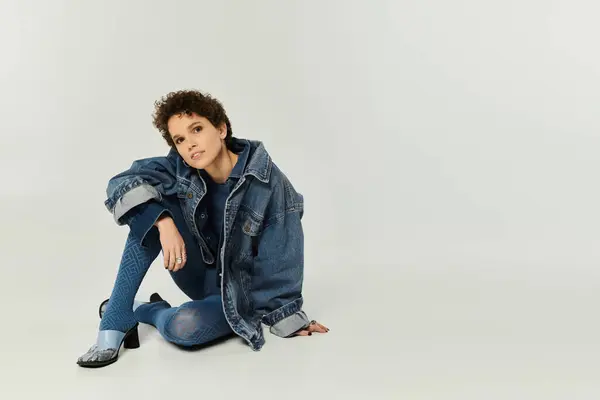 This young beautiful woman poses gracefully in a studio, highlighting her trendy denim outfit. — Stock Photo
